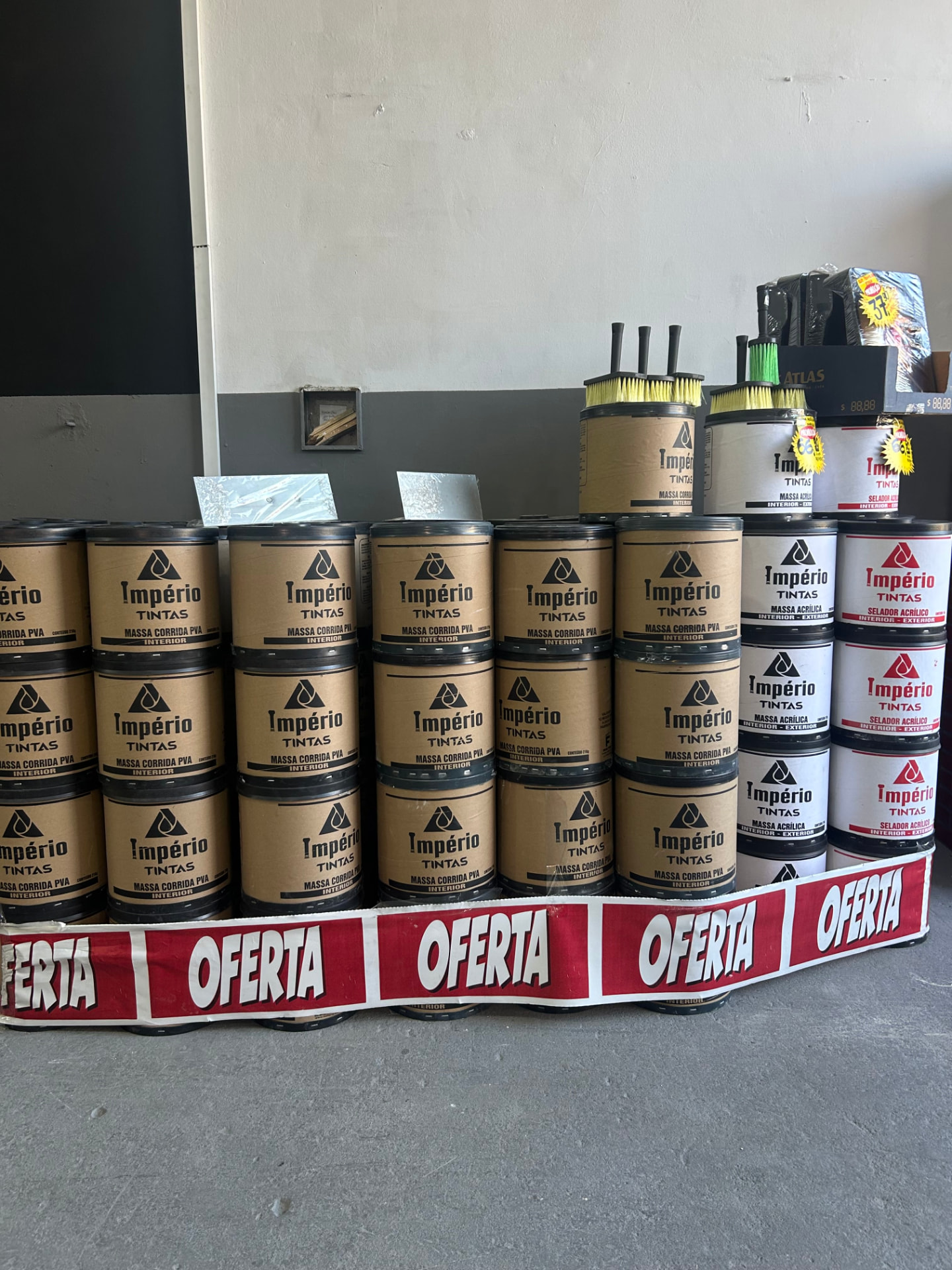 Latas de tinta e selador Império empilhadas com faixa de oferta